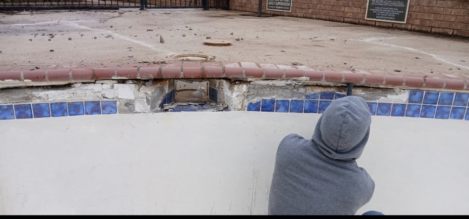 Close-up of damaged pool tile and coping before restoration
